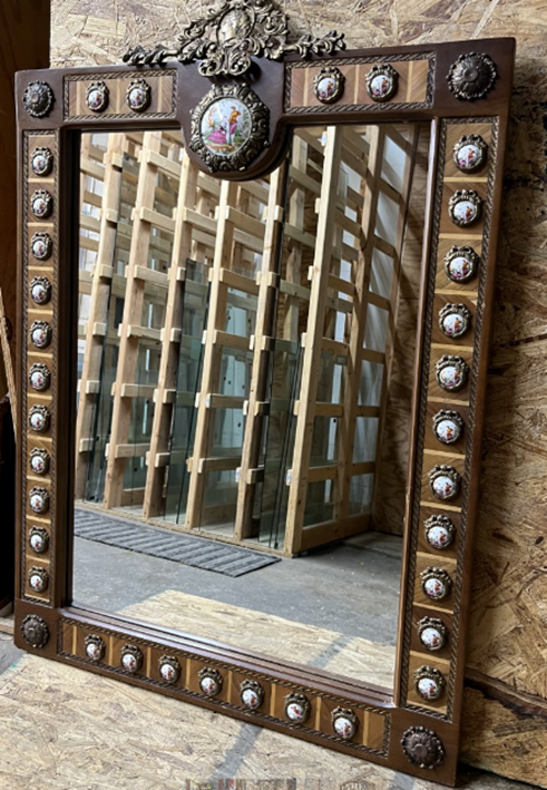 A mirror with metal studs and a decorative frame.