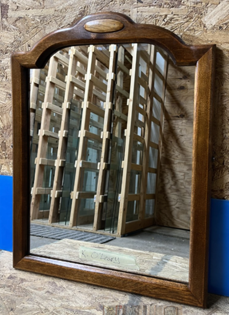 A mirror reflecting the wooden frame of an old building.