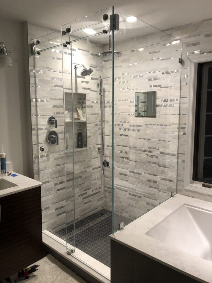 A bathroom with a glass shower door and white tile.